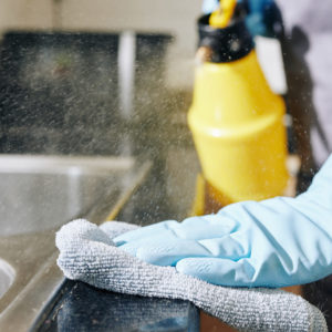 Housewife spraying kitchen surfaces with desinfectant and wiping off dirt and dust